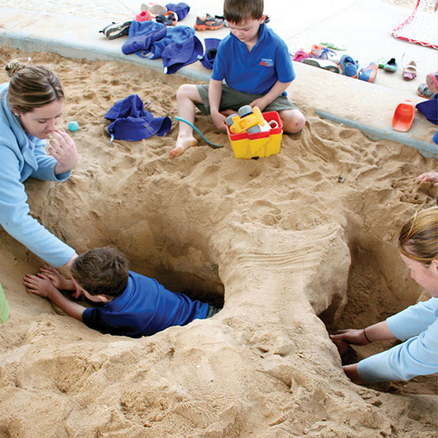 Photo of a child crawling under a sand bridge in the sand pit