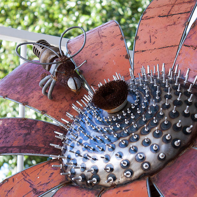 Metal sculpture of a bee pollinating a flower