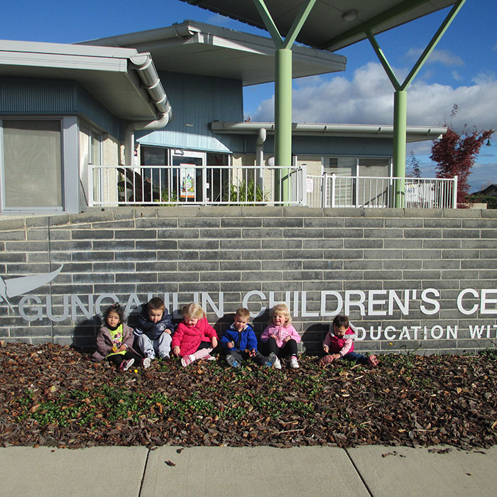 Photo of children sitting in front of the Gungahlin  Children's Centre sign